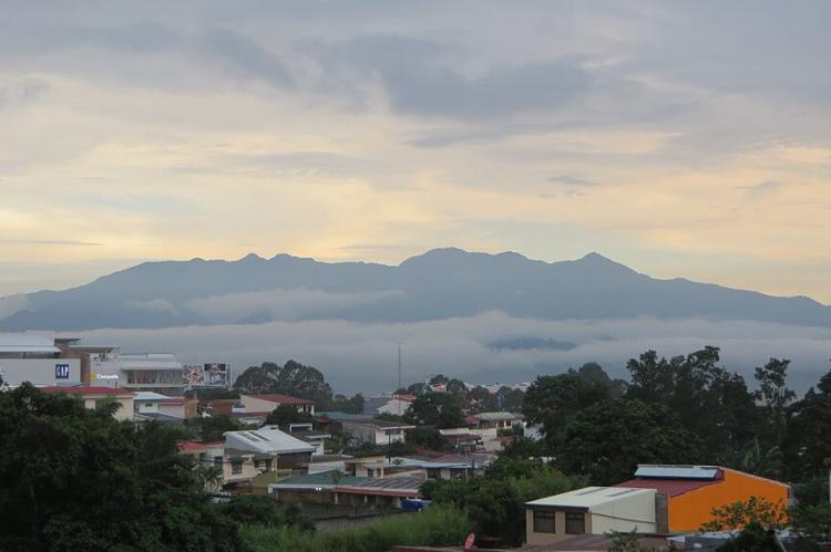 View of the Cerros de Escazú mountain range, city of San José lies under clouds in the Central Valley in the middle distance.