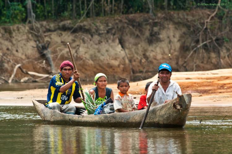 A family paddles down the upper Rupununi River in their dugout canoe, southwestern Guyana