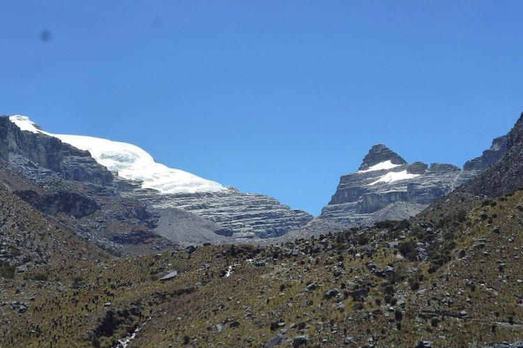 The side of Pan de Azúcar peak (left), seen through a broad valley with sparse páramo vegetation, Colombia